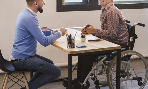 A manager and a colleague with disability working together at a desk
